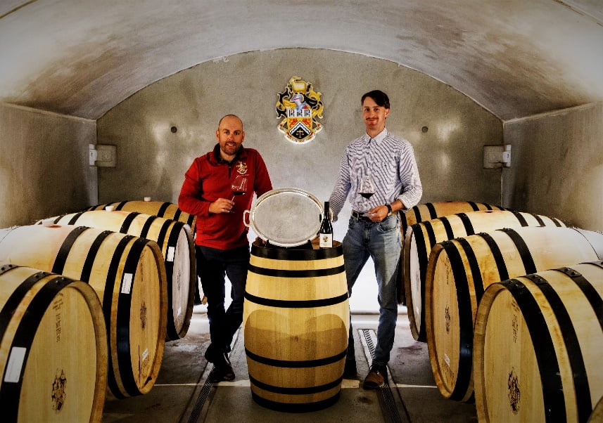 The 2022 Trophy Winners stand in a barrel room with their trophy plate