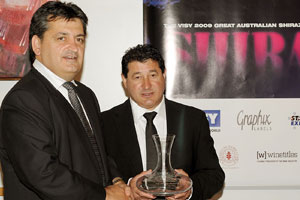 Two mean in suits, one holding a crystal carafe trophy.